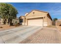 Tan house with a two-car garage and brick paver driveway at 23802 W Tamarisk Ave, Buckeye, AZ 85326