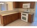 Corner view of a traditional kitchen with wooden cabinets, neutral countertops, and white appliances at 25609 N Forest Rd # 20, Rio Verde, AZ 85263