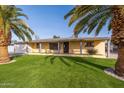 Front view of a single-story home with a spacious lawn and palm trees at 5452 E University Dr, Mesa, AZ 85205