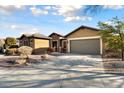 Tan house with a gray garage door and nicely landscaped yard at 20089 N 263Rd Dr, Buckeye, AZ 85396