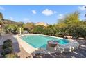 Backyard pool featuring decorative stone fire bowls, a stone surround, and mature desert landscaping at 20369 N 272Nd Ave, Buckeye, AZ 85396