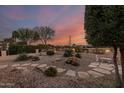 Landscaped backyard with fire pit, stone pathway, and desert plants at sunset at 23187 W Lasso Ln, Buckeye, AZ 85326