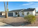 Updated single story home with rock landscaping and a gray garage door at 10001 N 87Th Ln, Peoria, AZ 85345