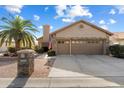 Single-story home with a two-car garage and palm tree at 10605 E Nacoma Dr, Sun Lakes, AZ 85248