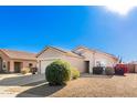 Tan house with a two-car garage and desert landscaping at 15365 W Caribbean Ln, Surprise, AZ 85379