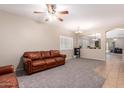 Open living room features neutral walls, a ceiling fan, and a comfortable leather sofa at 163 W Dragon Tree Ave, Queen Creek, AZ 85140