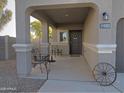 Covered porch with seating and a rustic wheel at 19203 N Marbella Ave, Maricopa, AZ 85138