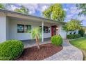 Inviting front porch with mature landscaping and a vibrant red front door at 3002 E Mitchell Dr, Phoenix, AZ 85016