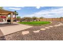 Expansive backyard featuring a well-maintained lawn, desert landscaping, a built-in barbecue, and a covered patio at 32504 N Cherry Creek Rd, San Tan Valley, AZ 85144
