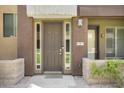 Front entrance of townhome with modern brown door and landscaping at 6605 N 93Rd Ave # 1087, Glendale, AZ 85305