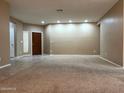 Spacious living room featuring neutral paint, carpet flooring, ample natural light, and a welcoming front door at 2335 W Muirfield Dr, Anthem, AZ 85086
