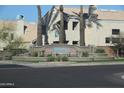 Community entrance with desert landscaping, tile-roofed buildings, and palm trees enhance the property's curb appeal at 15858 S 11Th Pl, Phoenix, AZ 85048