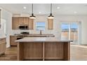 Modern kitchen with island, stainless steel appliances, and wood cabinets at 53929 W Bowlin Rd, Maricopa, AZ 85139