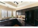 Modern kitchen featuring dark wood cabinets, granite countertops, and black appliances at 7760 E Pepper Tree Ln, Scottsdale, AZ 85250