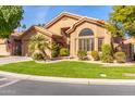 Tan house with a two-car garage and lush green lawn at 9428 W Taro Ln, Peoria, AZ 85382