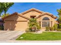 Tan house with a two-car garage and palm tree landscaping at 9428 W Taro Ln, Peoria, AZ 85382