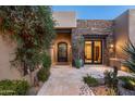 Elegant entry features a wrought-iron door, stonework, and a courtyard with mature plants at 10585 E Crescent Moon Dr # 19, Scottsdale, AZ 85262