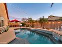 Swimming pool at twilight, accented with string lights and views of the inviting backyard patio area at 10851 E Sonrisa Ave, Mesa, AZ 85212