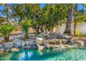 Backyard oasis with a pool, waterfall feature, and lush landscaping at 10041 N 52Nd Pl, Paradise Valley, AZ 85253
