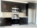 Modern kitchen featuring dark cabinetry, stainless steel appliances, and quartz countertops at 18366 W Poston Dr, Surprise, AZ 85387