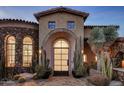 Stunning stone exterior of a luxury home with arched entryway and desert landscaping at 27256 N 97Th Pl, Scottsdale, AZ 85262