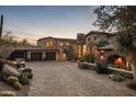 Luxury home with a large driveway and beautiful landscaping at dusk at 27256 N 97Th Pl, Scottsdale, AZ 85262