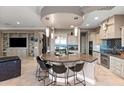 An open kitchen features a curved island with seating, stainless steel appliances, and tiled backsplash at 1457 E Copper Holw, Queen Creek, AZ 85140