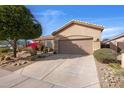 Single-story tan house with a two car garage and desert landscaping in the front yard at 7654 E Quill Ln, Scottsdale, AZ 85255