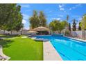 A luxurious pool surrounded by lush greenery and patio umbrellas at 2161 E Flintlock Way, Chandler, AZ 85286