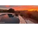 Relaxing backyard oasis featuring a sparkling pool, waterfall, and sunset views at 5306 N 188Th Ln, Litchfield Park, AZ 85340