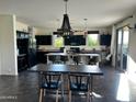 Modern kitchen with dark cabinets, an island, and a large dining table at 5306 N 188Th Ln, Litchfield Park, AZ 85340