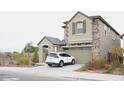 Two-story house with stone accents, a two-car garage, and a car parked in the driveway at 9556 W Sells Dr, Phoenix, AZ 85037