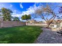 Backyard with grassy lawn, trees, and rock border at 10760 W Monte Vista Rd, Avondale, AZ 85392