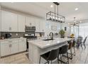 Modern kitchen with white cabinets, quartz island, and stainless steel appliances at 10994 W Mckinley St, Avondale, AZ 85323