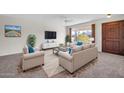 Living room with beige sofas, a coffee table, and a large window at 12611 W Gable Hill Dr, Sun City West, AZ 85375