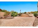 Tranquil backyard with a brick patio, desert landscaping, built-in seating, and an American flag at 5010 E Mesquite Wood Ct, Phoenix, AZ 85044