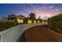 A winding driveway leads to this home that features a quaint white fence and mature landscaping at twilight at 5249 E Thunderbird Rd, Scottsdale, AZ 85254