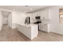 Open-concept kitchen with island featuring stainless appliances, white cabinets, and a stylish black faucet at 18219 W Hess St, Goodyear, AZ 85338