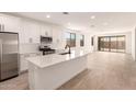 Bright, open kitchen and living area with stainless appliances, kitchen island, and sliding glass doors to the backyard at 18219 W Hess St, Goodyear, AZ 85338