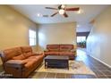 Cozy living room featuring two brown leather couches and a coffee table at 35706 W Costa Blanca Dr, Maricopa, AZ 85138