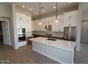 Spacious kitchen featuring white cabinetry, stainless steel appliances, a large island, and modern pendant lighting at 6818 N 190Th Ave, Waddell, AZ 85355