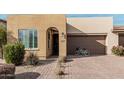 Tan house with a two-car garage and landscaped front yard with a bike at 880 E Verde Blvd, Queen Creek, AZ 85140