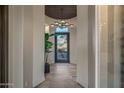 Modern entryway featuring a glass-enclosed wine room and elegant light fixture at 3021 W Feather Sound Dr, Phoenix, AZ 85086