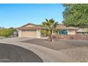 Front view of a tan brick ranch home with a palm tree and gravel driveway at 10312 W Sierra Dawn Dr, Sun City, AZ 85351