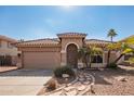 Tan house with a two-car garage, arched entryway, and stone pathway at 15839 W Calavar Rd, Surprise, AZ 85379