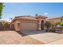 Tan house exterior with a two-car garage and a gravel pathway at 15839 W Calavar Rd, Surprise, AZ 85379