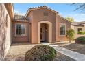 Front entry of a tan house with arched entryway and desert landscaping at 20533 N Sequoia Crest Dr, Surprise, AZ 85387