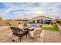 An outdoor seating area with a firepit, set in a lush yard with lounge chairs by the pool at 23933 N 167Th Ln, Surprise, AZ 85387