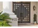 Close-up of the elegant front door with decorative windows, set against a stucco facade and lush greenery at 402 E Windmere Dr, Phoenix, AZ 85048