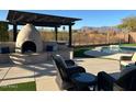 Covered patio area with a fireplace, outdoor seating, and backyard views with mature landscaping at 9900 E Desert Trail Ln, Gold Canyon, AZ 85118